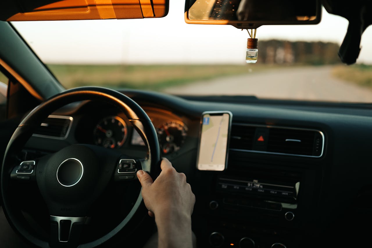 Interior of a car with GPS navigation, focusing on the driver and dashboard during the day.